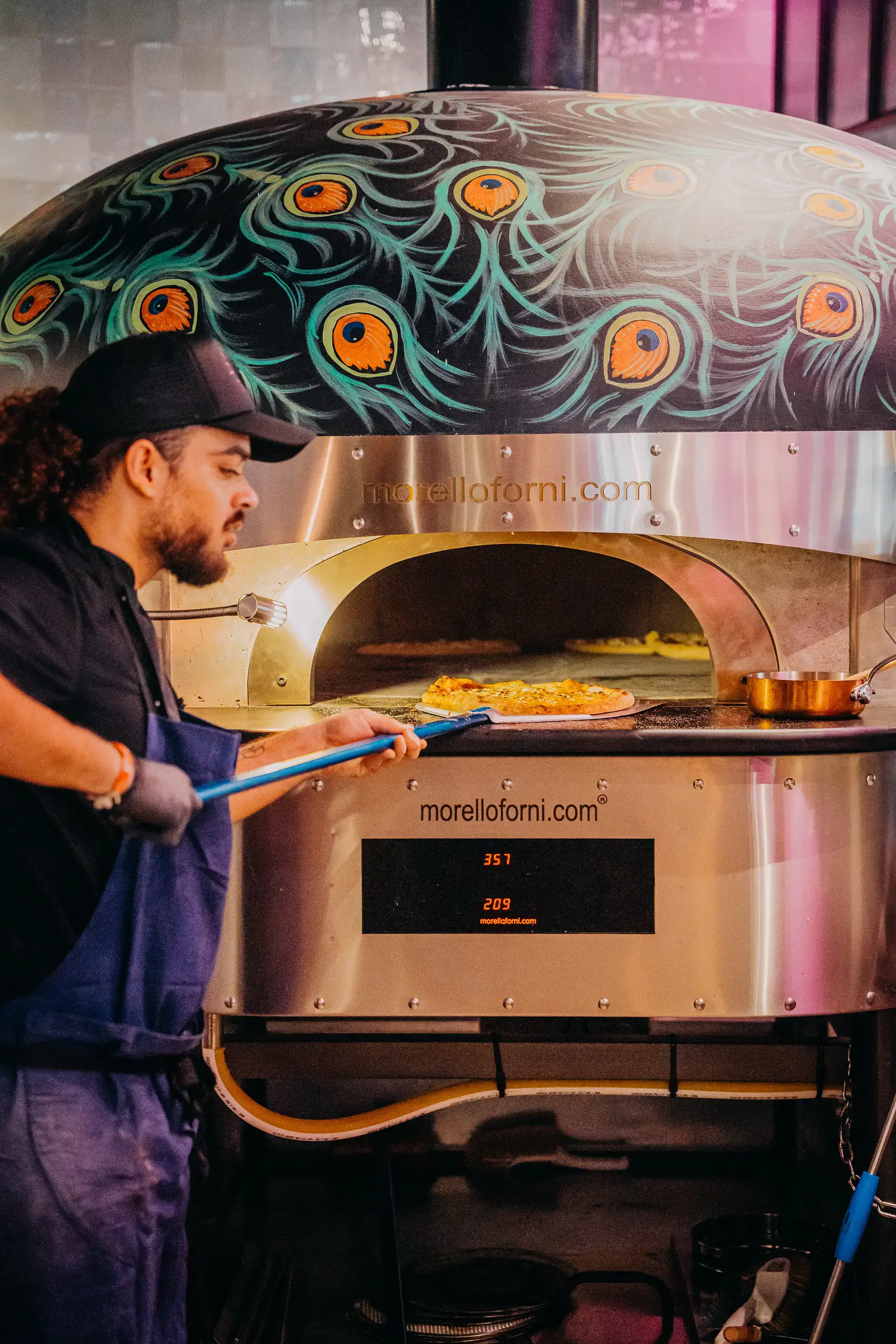 Photo d'un pizzaiolo en train de sortir une pizza du four