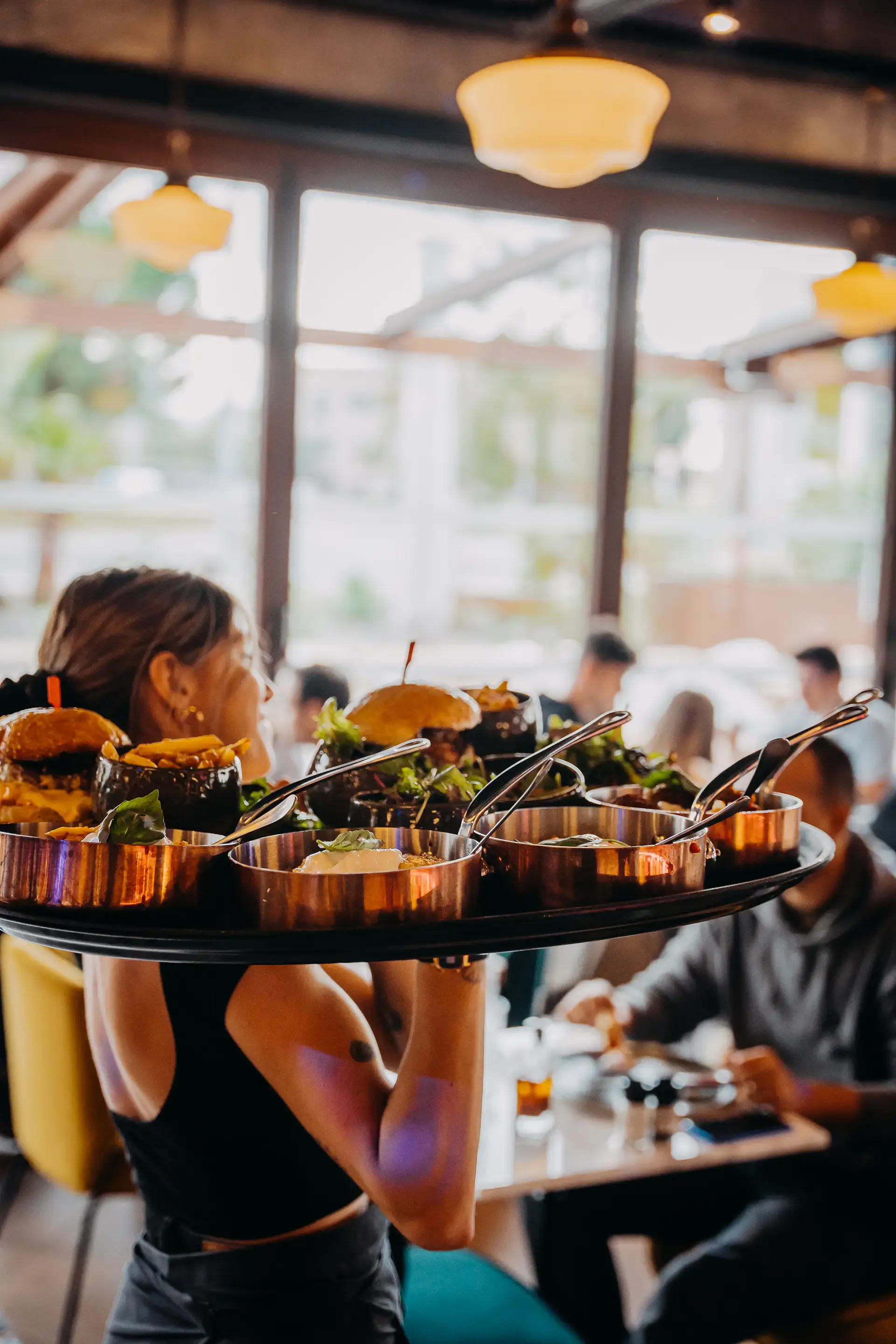 Photo d'une serveuse qui porte un plateau rempli de burgers appétissants